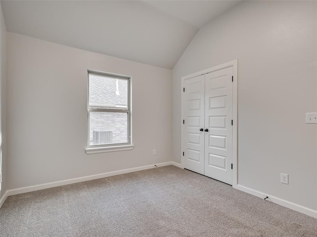 unfurnished bedroom with carpet flooring, lofted ceiling, and a closet