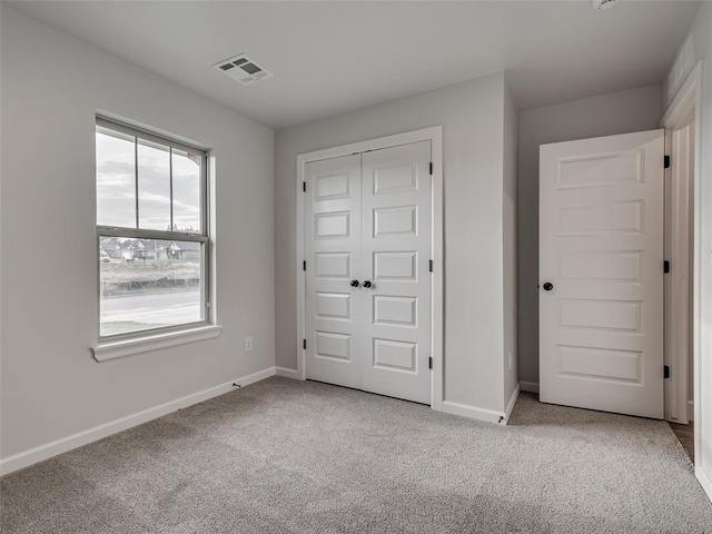 unfurnished bedroom with light colored carpet and a closet