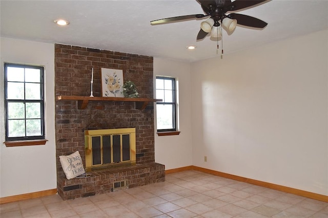 unfurnished living room with a fireplace, ceiling fan, plenty of natural light, and light tile patterned floors