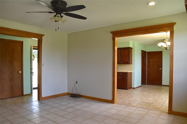 spare room with light tile patterned floors and ceiling fan with notable chandelier