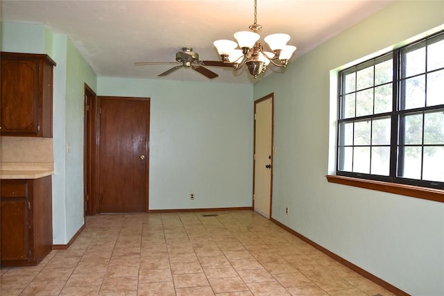 unfurnished dining area featuring ceiling fan with notable chandelier