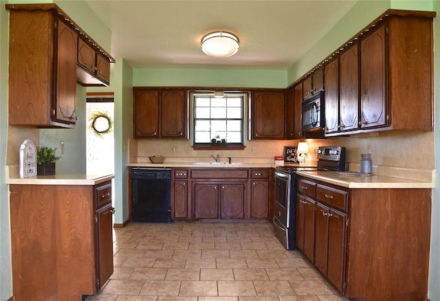 kitchen featuring dark brown cabinetry, sink, and black appliances