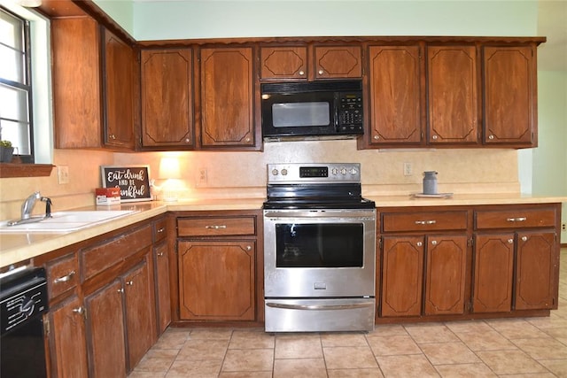 kitchen featuring sink, light tile patterned flooring, and black appliances