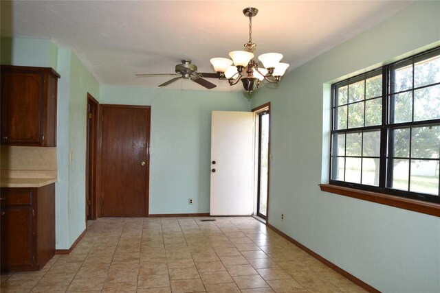 tiled empty room with ceiling fan with notable chandelier