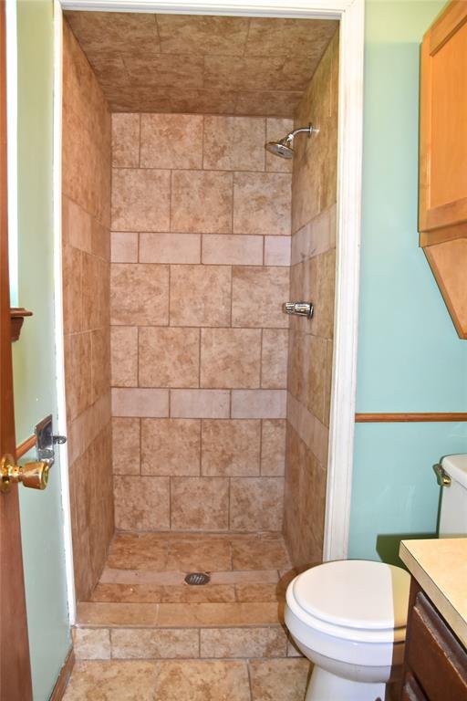 bathroom featuring tiled shower, vanity, and toilet