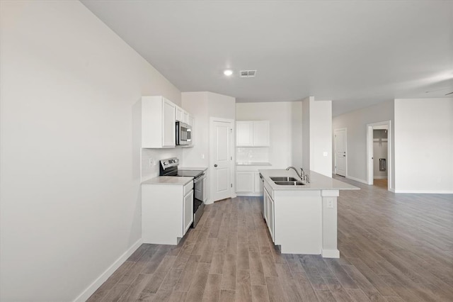 kitchen featuring appliances with stainless steel finishes, an island with sink, sink, white cabinets, and decorative backsplash