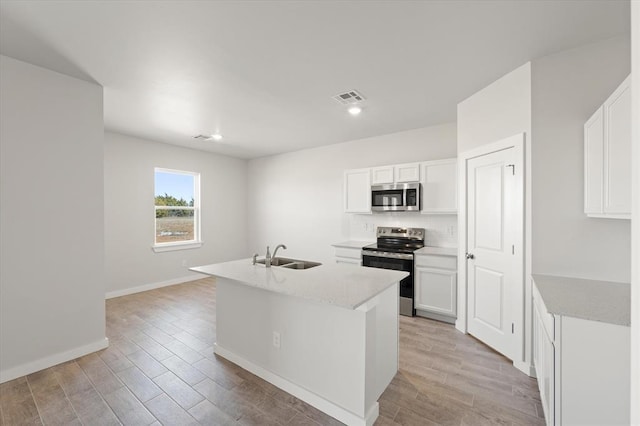 kitchen featuring sink, light hardwood / wood-style flooring, white cabinetry, stainless steel appliances, and a center island with sink