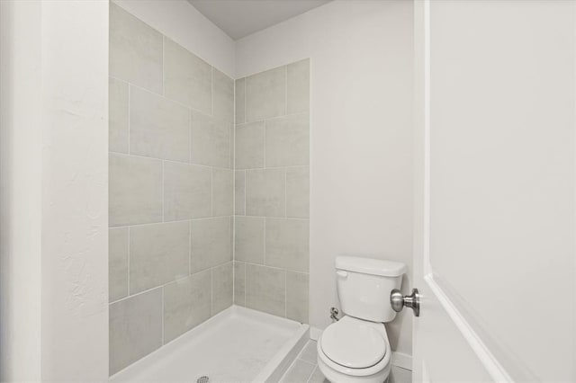 bathroom featuring a tile shower and toilet