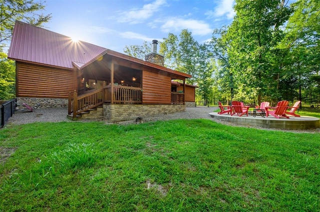 back of house featuring a lawn, a patio area, and a fire pit