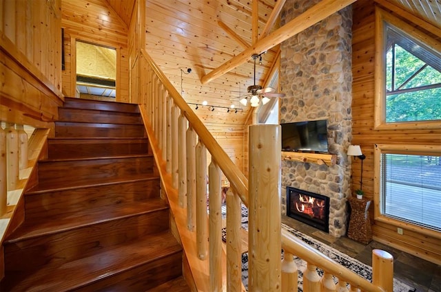 stairway with wooden walls, a fireplace, beamed ceiling, and wood ceiling