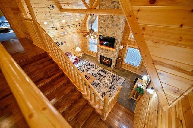 stairway featuring a stone fireplace, wooden walls, hardwood / wood-style floors, and ceiling fan