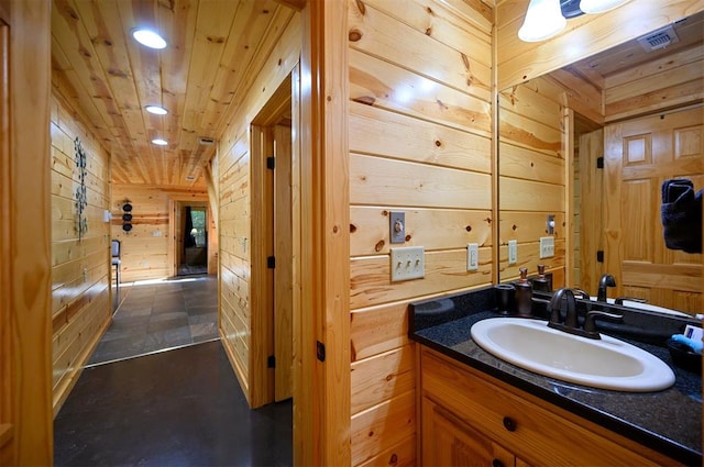 bathroom with vanity, wooden walls, and wood ceiling