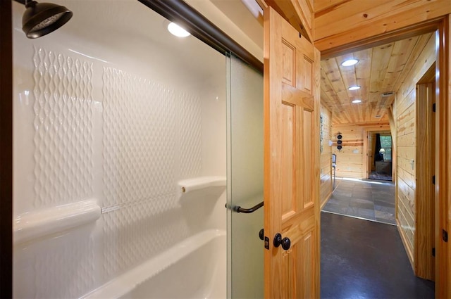 bathroom featuring wood walls, concrete floors, and a shower with shower door