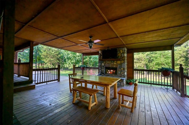 wooden deck with an outdoor stone fireplace and ceiling fan