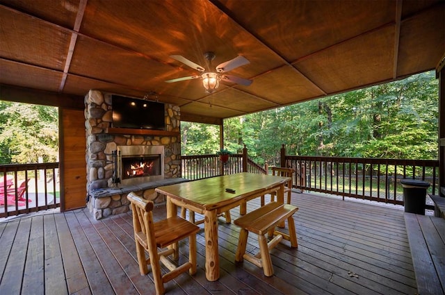 wooden terrace with an outdoor stone fireplace and ceiling fan