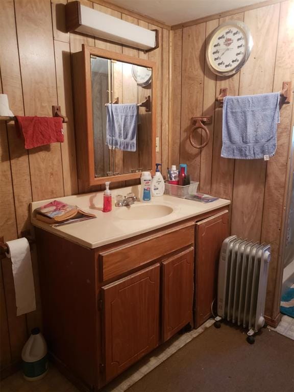 bathroom featuring vanity, radiator heating unit, and wood walls