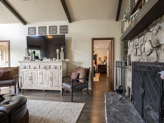 living room featuring vaulted ceiling with beams, a stone fireplace, and dark hardwood / wood-style flooring