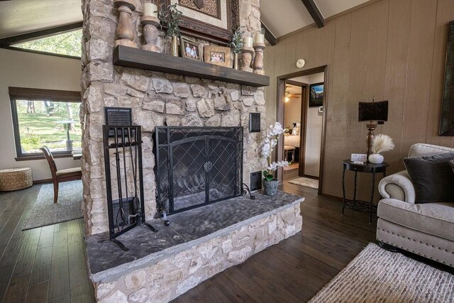 living room featuring beam ceiling, a stone fireplace, plenty of natural light, and dark hardwood / wood-style floors