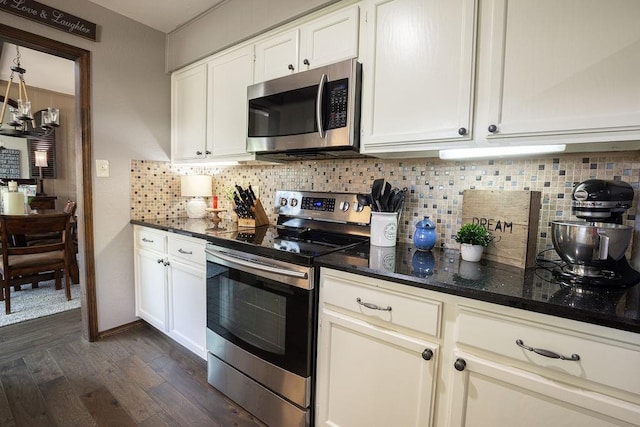 kitchen with stainless steel appliances, white cabinetry, dark hardwood / wood-style floors, and dark stone countertops