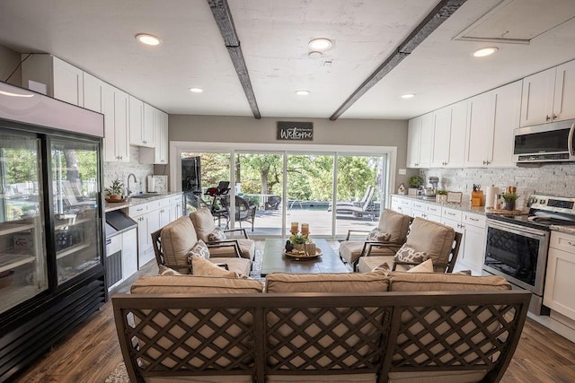 kitchen with white cabinets, beamed ceiling, stainless steel appliances, and dark wood-type flooring