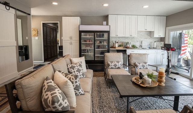 kitchen with black refrigerator, a barn door, white cabinets, and tasteful backsplash