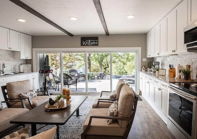 living room featuring sink, beamed ceiling, and dark hardwood / wood-style floors