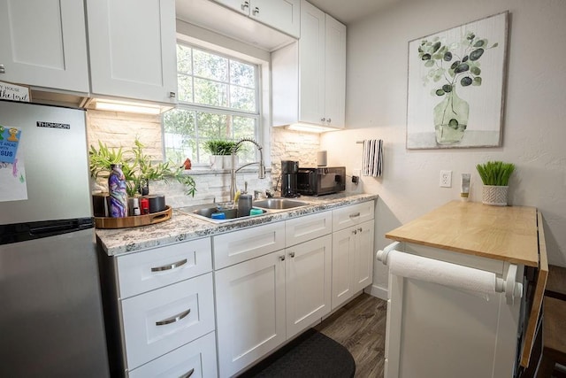 4545 Chickasaw Trl, Sulphur, OK 73086 - kitchen featuring freestanding refrigerator, a sink, white cabinetry, and tasteful backsplash