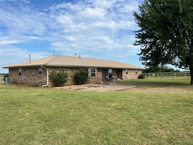 rear view of house with a patio, central AC, and a lawn