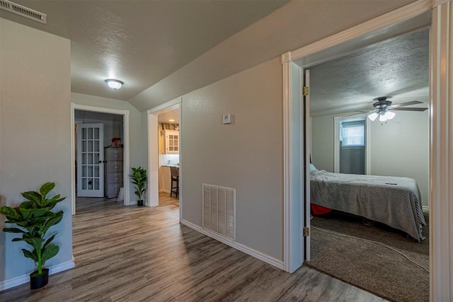 corridor with wood-type flooring and a textured ceiling