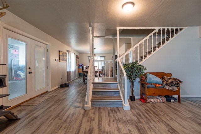 foyer entrance with hardwood / wood-style flooring, a textured ceiling, and french doors