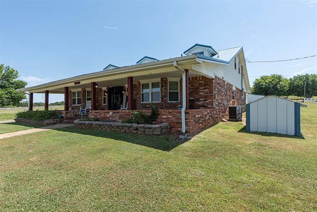 view of front of property featuring cooling unit, a storage shed, a front yard, and covered porch