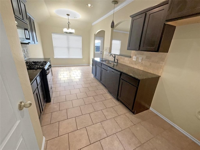 kitchen with backsplash, dark stone counters, sink, decorative light fixtures, and stainless steel appliances