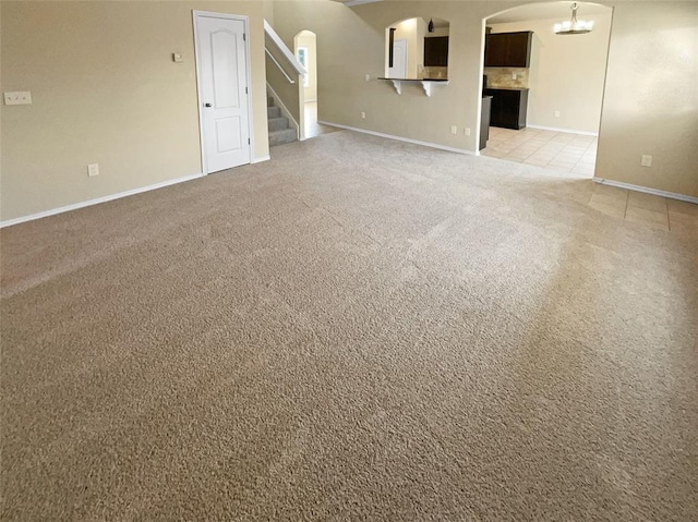 unfurnished living room featuring light colored carpet and a notable chandelier