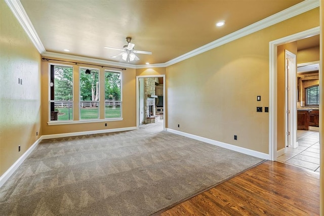 unfurnished room featuring crown molding, ceiling fan, light hardwood / wood-style floors, and a brick fireplace