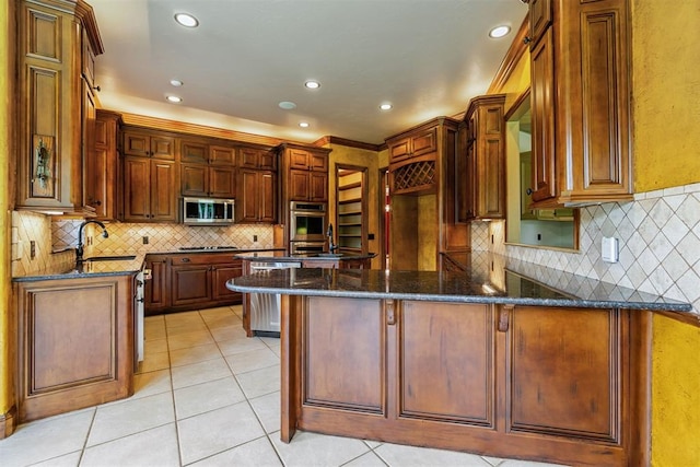 kitchen with kitchen peninsula, stainless steel appliances, sink, light tile patterned floors, and dark stone countertops