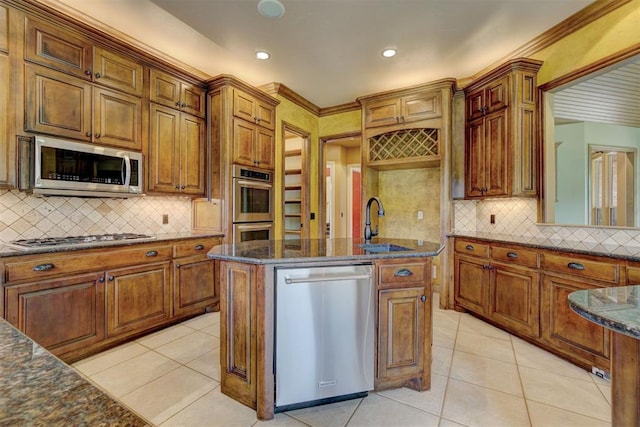 kitchen featuring tasteful backsplash, stainless steel appliances, sink, light tile patterned floors, and a center island