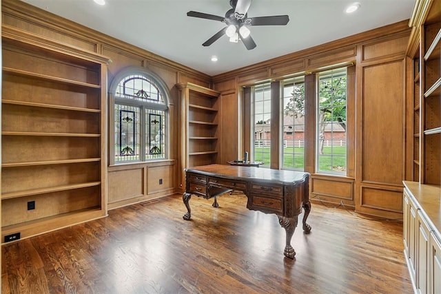 office area featuring ceiling fan, dark hardwood / wood-style flooring, wood walls, and built in features