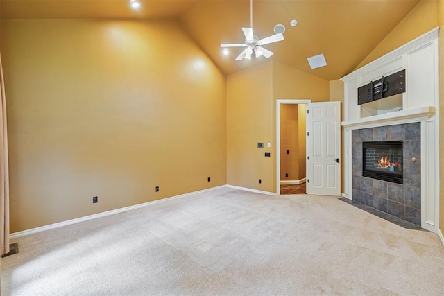 unfurnished living room featuring a tile fireplace, ceiling fan, high vaulted ceiling, and light colored carpet