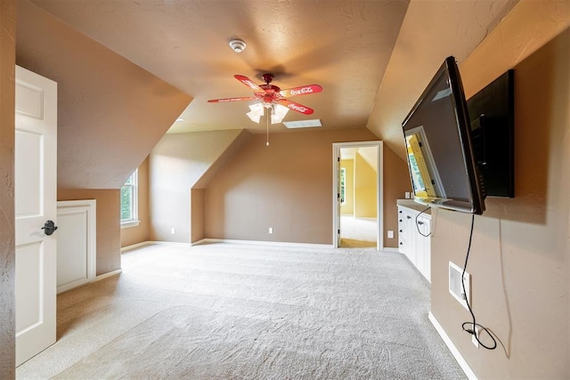 bonus room with a textured ceiling, light colored carpet, vaulted ceiling, and ceiling fan