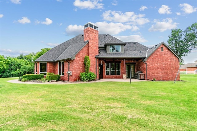 rear view of property featuring a lawn and a patio area