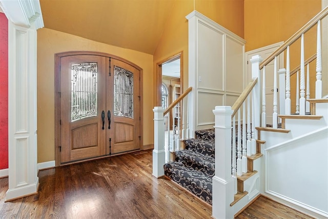 entryway with wood finished floors, vaulted ceiling, and stairway