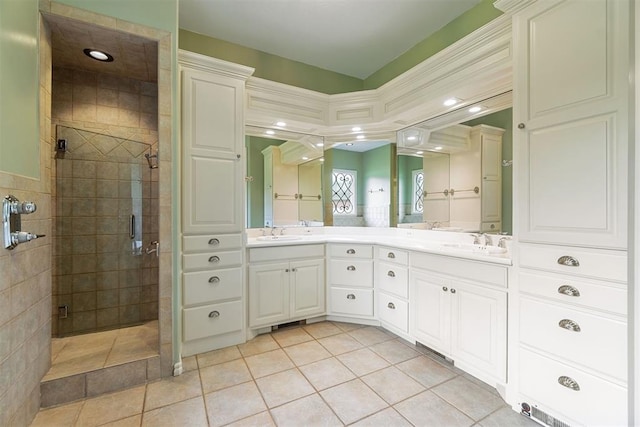 bathroom with double vanity, a sink, a tile shower, and tile patterned floors