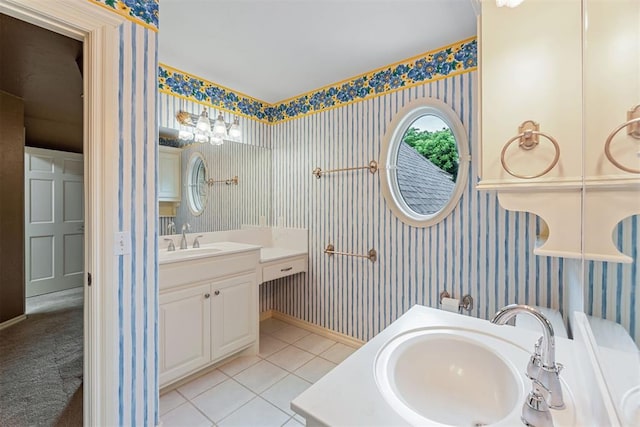 bathroom featuring wallpapered walls, tile patterned flooring, a sink, and two vanities