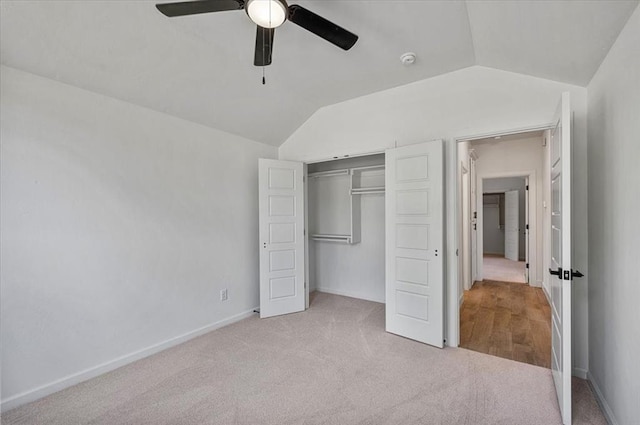 unfurnished bedroom featuring light carpet, a closet, vaulted ceiling, and ceiling fan