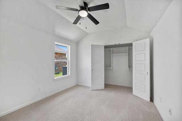 unfurnished bedroom featuring ceiling fan, light colored carpet, lofted ceiling, and a closet