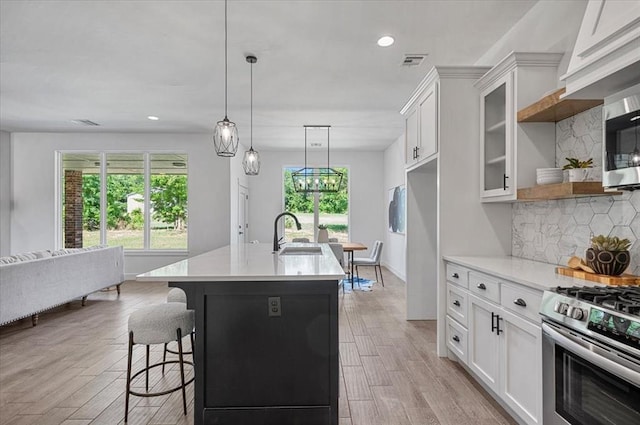 kitchen with tasteful backsplash, white cabinetry, sink, and light wood-type flooring