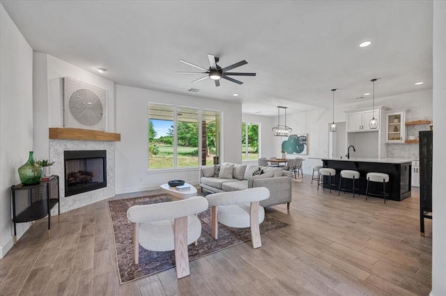 living room with ceiling fan, light hardwood / wood-style floors, and sink