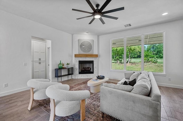 living room featuring ceiling fan, wood-type flooring, and a premium fireplace