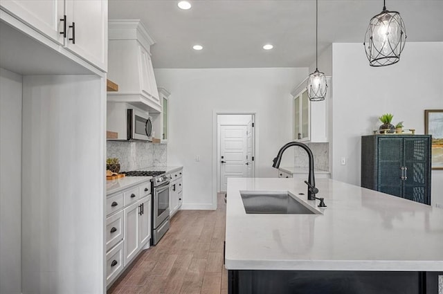 kitchen featuring stainless steel appliances, sink, decorative light fixtures, light hardwood / wood-style flooring, and white cabinetry