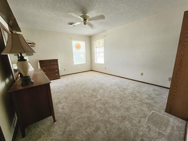 unfurnished bedroom with ceiling fan, light colored carpet, and a textured ceiling